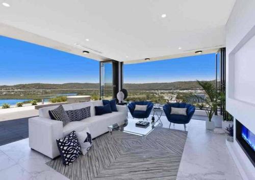 ein Wohnzimmer mit einem weißen Sofa und blauen Stühlen in der Unterkunft Stylish Penthouse with Views & Jacuzzi in Gosford