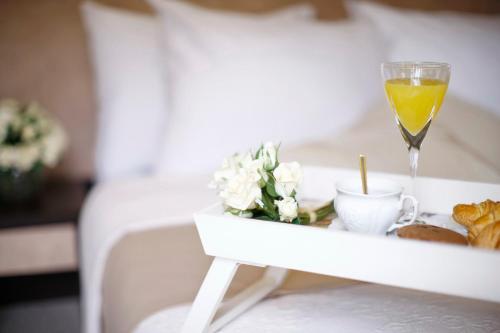 ein Tablett mit Essen und ein Glas Wein auf dem Bett in der Unterkunft Garni Hotel Vozarev in Belgrad