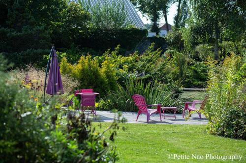 - une table, des chaises et un parasol dans le jardin dans l'établissement Au Jardin des Deux Ponts, à Abbeville