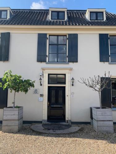 a white house with a black door and two trees at The Riverside Logies & Restaurant in Maarssen