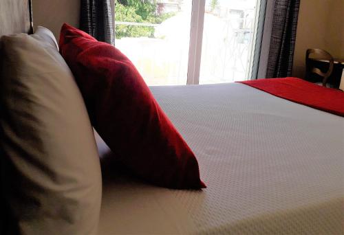 - un lit avec des oreillers rouges et blancs et une fenêtre dans l'établissement Hotel Noucentista, à Sitges