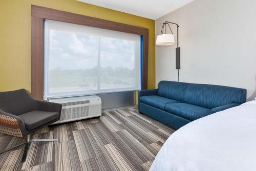 une chambre d'hôtel avec un lit, une chaise et une fenêtre dans l'établissement Holiday Inn Express & Suites - Grand Rapids Airport - South, an IHG Hotel, à Grand Rapids