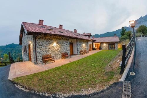 ein Steinhaus mit einer Bank an der Seite einer Straße in der Unterkunft Apartamentos Los Picos de Europa in Colio