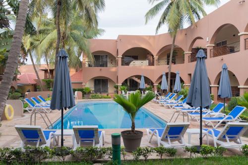 einen Pool im Resort mit Stühlen und Sonnenschirmen in der Unterkunft Airport Hotel Casino du Cap-vert in Dakar