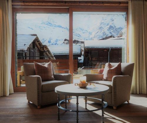 ein Wohnzimmer mit 2 Stühlen und einem Tisch in der Unterkunft The Capra Saas-Fee in Saas-Fee