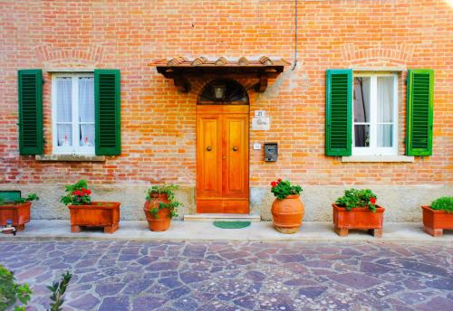 un edificio in mattoni con persiane verdi e porta in legno di Casa Fonte di Bacco a San Miniato