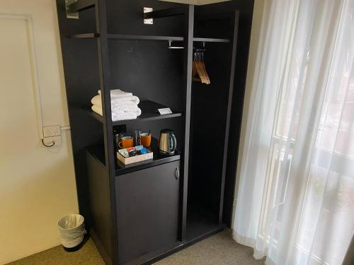 een zwarte boekenplank in een kamer met een raam bij Silkari Urban CKS Sydney Airport Hotel in Sydney