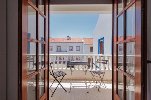 einen Balkon mit einem Tisch und Stühlen in der Unterkunft Zambujeira do Mar 4-Bed House Perfect for Families & Friends in Zambujeira do Mar