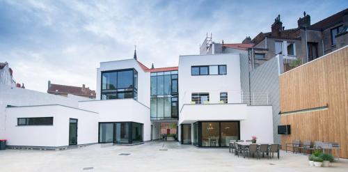 ein weißes Haus mit einem Innenhof vor einigen Gebäuden in der Unterkunft Villa Fluisterbos in Ostende