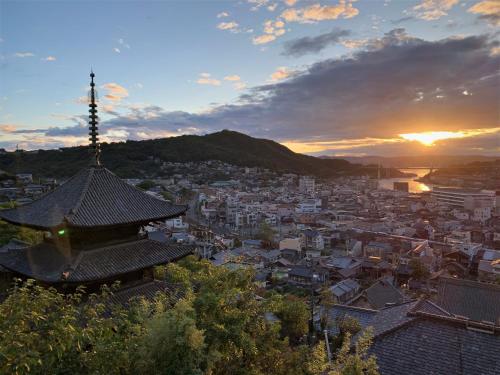 - une vue sur une ville au coucher du soleil avec une pagode dans l'établissement Onomichi Guest House Miharashi-tei, à Onomichi