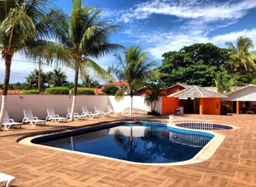 een zwembad met stoelen en palmbomen in een resort bij Villa Solarium Pousada in Cabo Frio