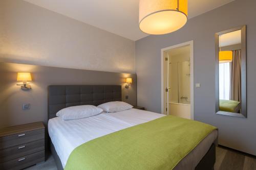 een slaapkamer met een groot bed en een groene deken bij Thon Hotel Residence Parnasse Aparthotel in Brussel