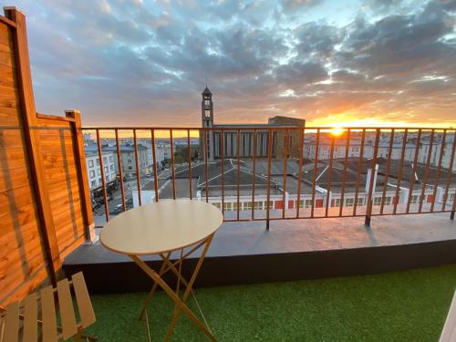 einen Balkon mit einem Tisch und Blick auf einen Uhrturm in der Unterkunft Hotel Saint Louis in Brest