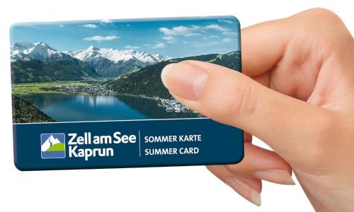 eine Hand mit einer Visitenkarte mit einem See und Bergen in der Unterkunft Apartment 5 Peaks in Zell am See