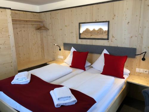 1 dormitorio con 2 camas y almohadas rojas y blancas en Berghotel Türlwand, en Ramsau am Dachstein