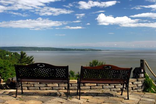 2 bancs installés sur un mur en pierre donnant sur un lac dans l'établissement Gîte Au Perchoir, à Baie-Saint-Paul