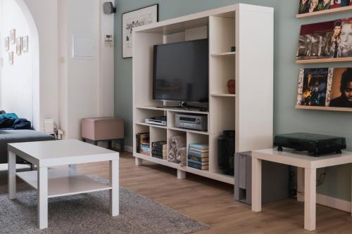 een woonkamer met een tv en een witte boekenplank bij Zus of So in Oostende