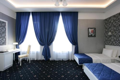 een hotelkamer met blauwe gordijnen, een bed en een bureau bij Hotel Litera in Dnipro