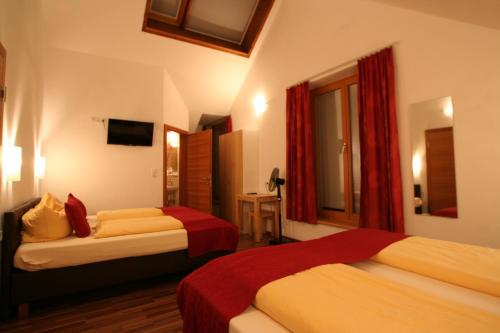 Cette chambre d'hôtel comprend 2 lits avec des rideaux rouges. dans l'établissement Hotel Engl, à Innsbruck