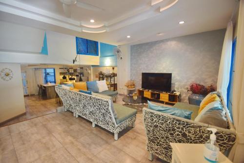 uma sala de estar com sofás e uma televisão de ecrã plano em Blu Beach Haven em Hua Hin