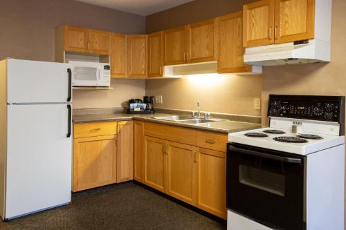 cocina con armarios de madera y nevera blanca en Lobstick Lodge, en Jasper