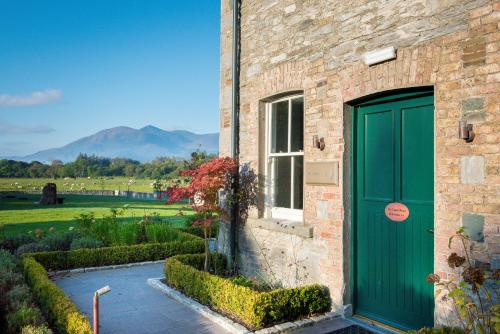 uma porta verde ao lado de um edifício de tijolos com jardim em Cahernane House Hotel em Killarney