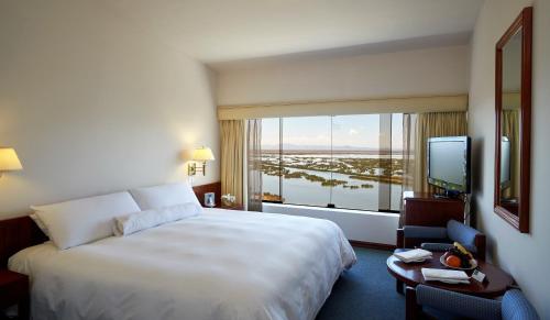 Habitación de hotel con cama grande y ventana grande. en GHL Hotel Lago Titicaca, en Puno