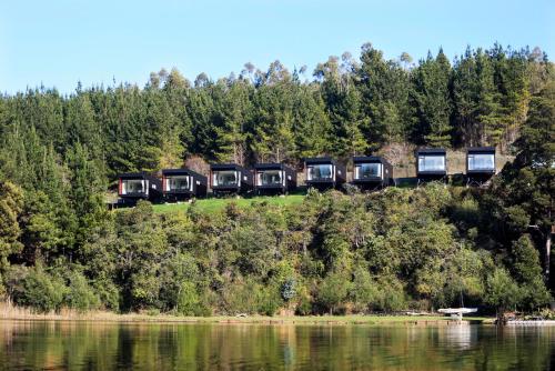 een trein op een heuvel naast een waterlichaam bij Pura Lodge in Concepción