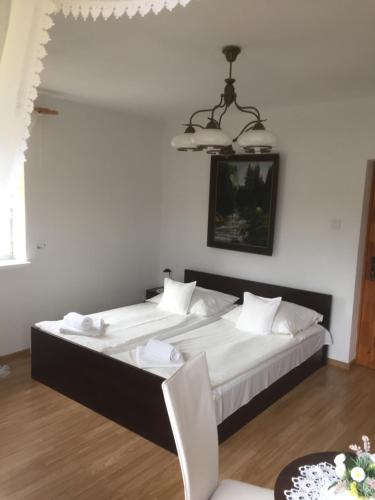 een slaapkamer met een groot bed met witte lakens en een kroonluchter bij Willa Panorama in Szczyrk