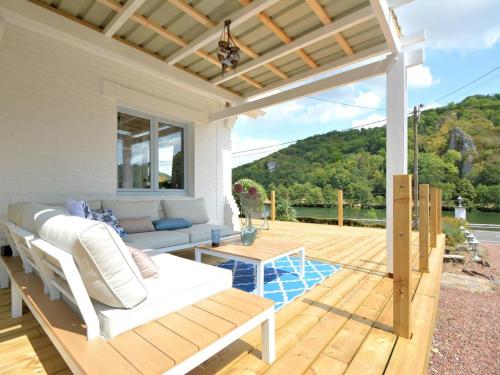 a patio with a couch and a table on a deck at Villa Waulsort in Waulsort