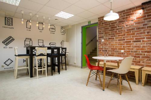 um quarto com mesas e cadeiras e uma parede de tijolos em Moon Hostel Gdańsk em Gdańsk