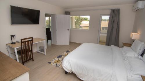 1 dormitorio con cama, mesa y escritorio en New Brookfields Hotel, en Freetown