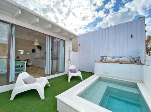 um pátio com uma piscina e 2 cadeiras brancas em Fridays Flats Casa Aquamarine em Barcelona