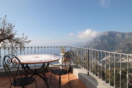 un tavolo e sedie su un balcone con vista sulle montagne di Villa Casola B&B a Positano