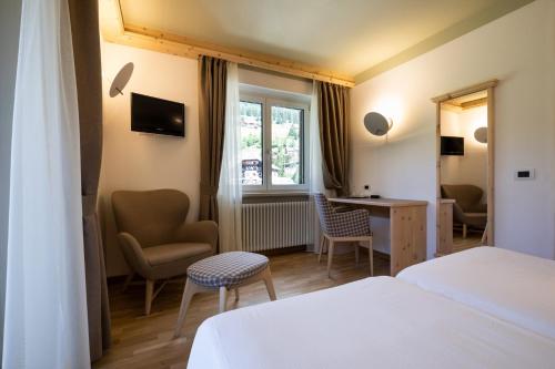 a hotel room with a bed and a desk and chairs at Hotel Medil in Campitello di Fassa