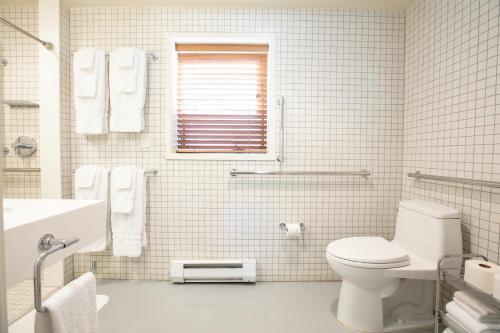 a white tiled bathroom with a toilet and a sink at Little Beaver Inn in Green Mountain Falls