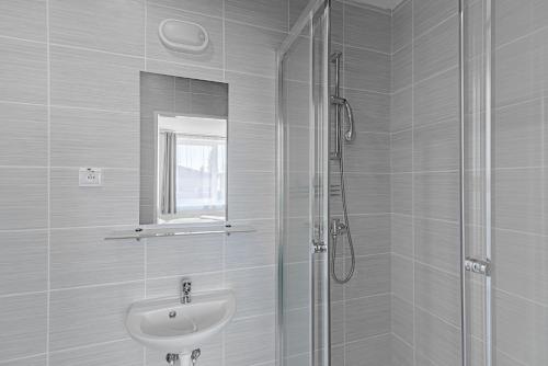 een witte badkamer met een wastafel en een douche bij Garni Hotel 31 in Spišská Nová Ves