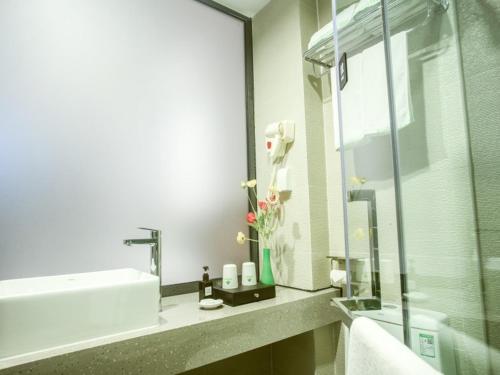 a bathroom with a sink and a glass shower at GreenTree Inn Haikou Haixiu Middle Road in Haikou