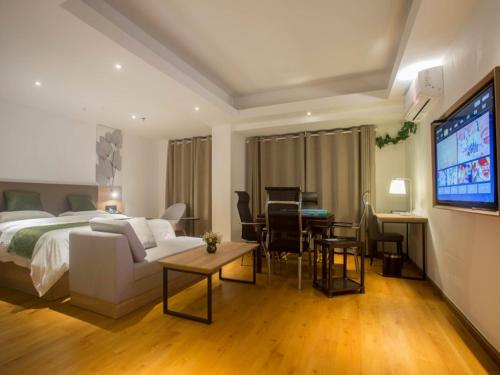 a bedroom with a bed and a living room with a tv at GreenTree Inn Haikou Haixiu Middle Road in Haikou