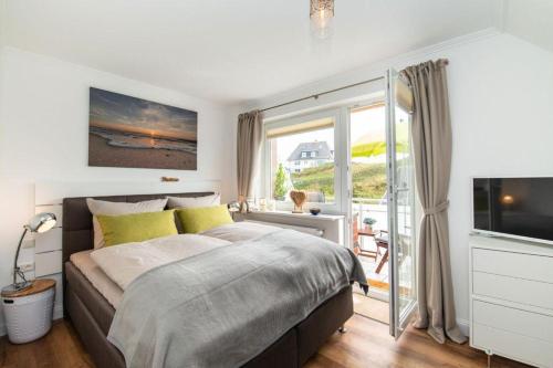 a bedroom with a bed and a television and a balcony at Appartement-Leuchtturmblick in Hörnum