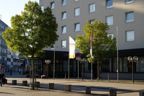 un bâtiment avec des drapeaux et des arbres devant lui dans l'établissement PLAZA Hotel Hanau, à Hanau