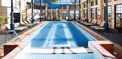 einen Pool mit Liegestühlen in einem Gebäude in der Unterkunft Stamford Grand Adelaide in Adelaide