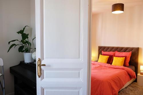 - une chambre dotée d'un lit avec des oreillers orange et jaune dans l'établissement Anna's Home Sweet Home, à Boulogne-Billancourt