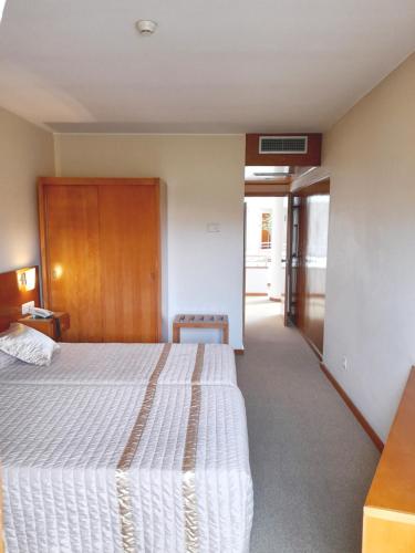 une chambre d'hôtel avec un lit et un couloir dans l'établissement Hotel das Taipas, à Guimarães