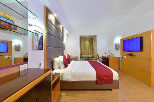 ein Hotelzimmer mit einem Bett und einem TV in der Unterkunft The Central Residency in Thiruvananthapuram