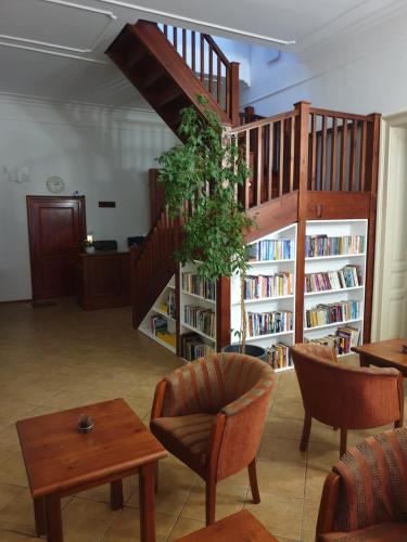 a library with a staircase and chairs and books at Pribina Penzión in Nitra