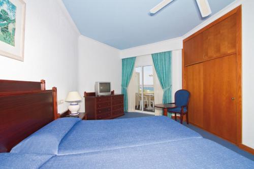 een slaapkamer met een blauw bed, een bureau en een raam bij Hotel Riu Oliva Beach Resort - All Inclusive in Corralejo