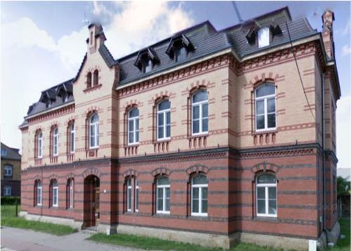 un grand bâtiment en briques avec un toit noir dans l'établissement Zimmerfrei-Dresden mit Bad-Miniküche Self Check In 24-7, à Dresde