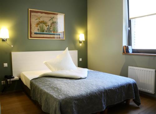 Un dormitorio con una cama con almohadas blancas. en Le Presbytère, en Differdange