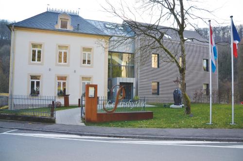 una casa blanca con banderas delante en Le Presbytère, en Differdange